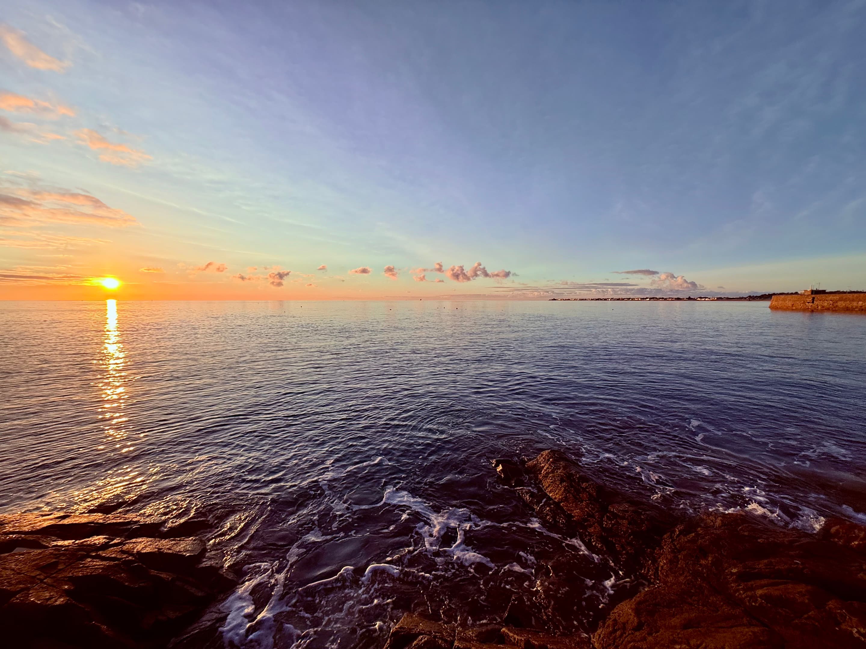 Sunset over the sea from a rocky shoreline, Jersey