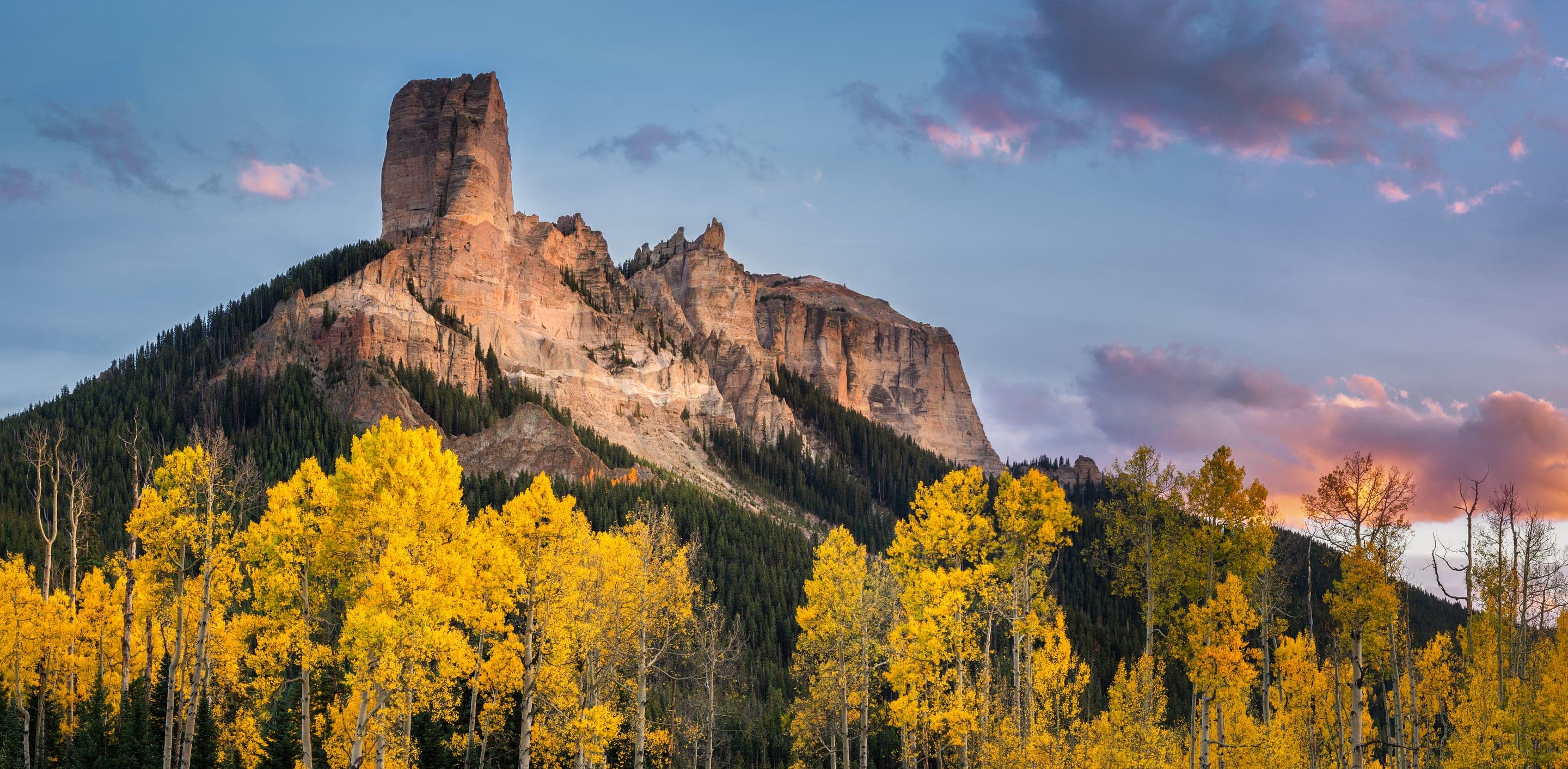 Mountain peak above autumn aspens at sunset